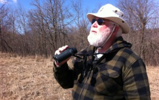 Man with Beard and Hat Looks for Raptors with Binoculars