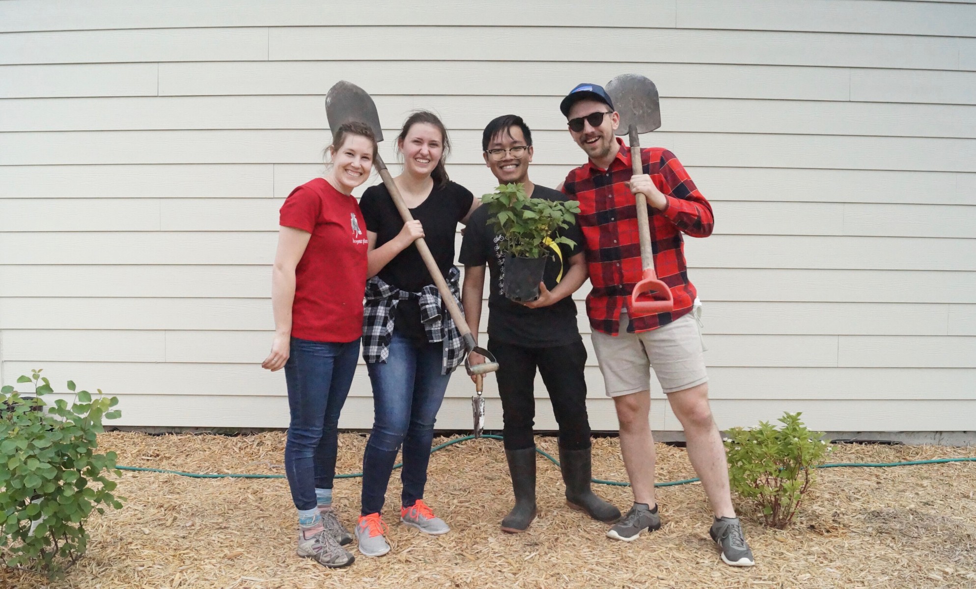 Group of 4 A Rocha volunteers and staff holding gardening equipment and smiling.