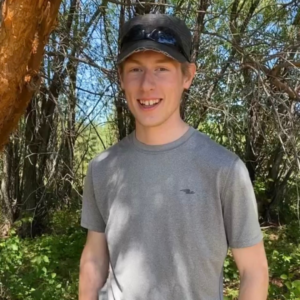 Graham Peters, young man, smiling in front of trees.