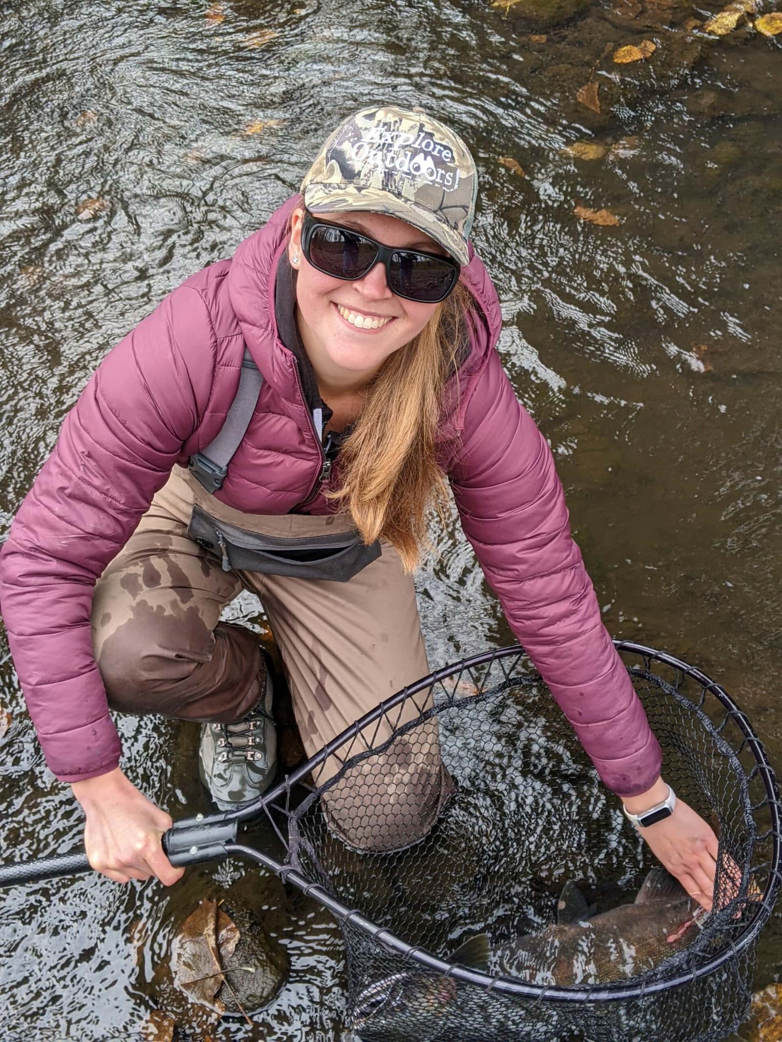 female angler holding net with coho salmon in it