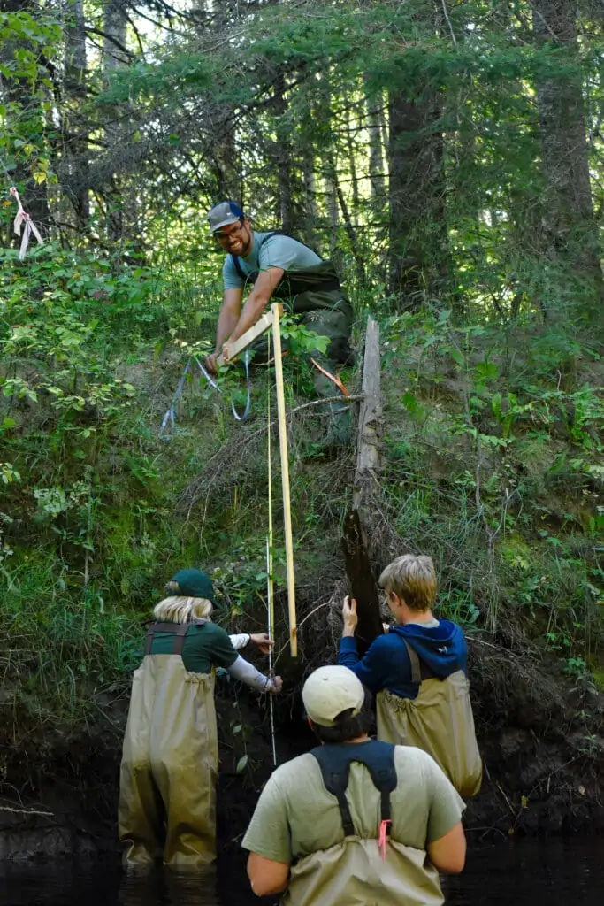 4 People measuring the height of a river bank
