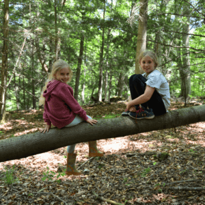 Two girls sitting on a fallen log.