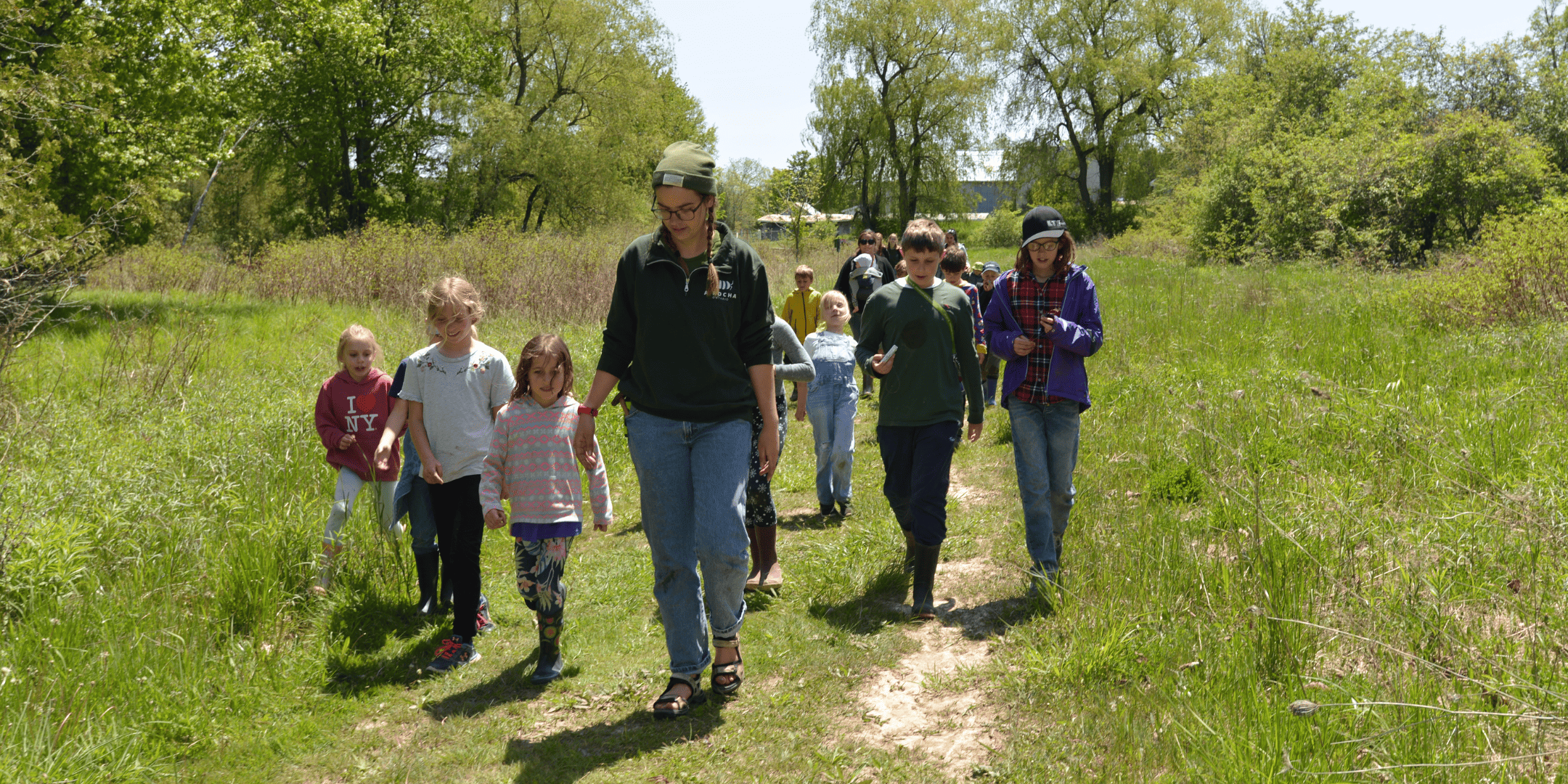 Jacoba, Program Coordinator, leading a group of children on a walk in the field.