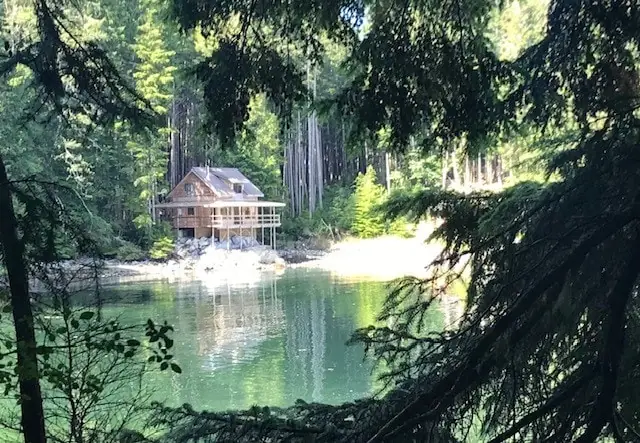 cabin in the forest next to water 