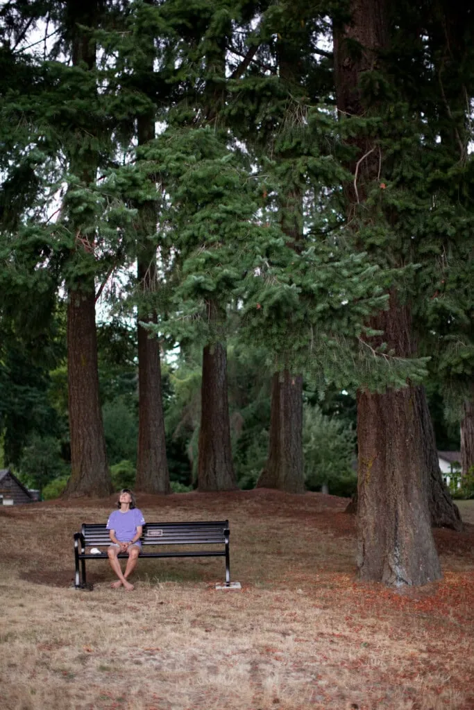A person relaxes on a bench, surrounded by greenery and the tranquility of the outdoors.
